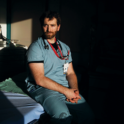 Matt douma sitting on a hospital bed in scrubs
