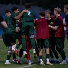 A group of player's from UFV's men's soccer team are smiling together and celebrating on the soccer field