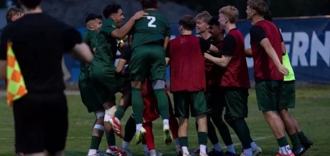 A group of player's from UFV's men's soccer team are smiling together and celebrating on the soccer field